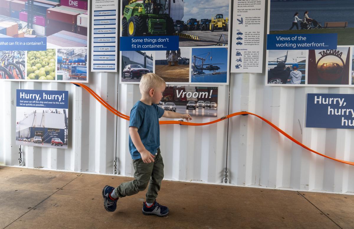 A boy plays with the interactive activity in the Port's educational shipping container